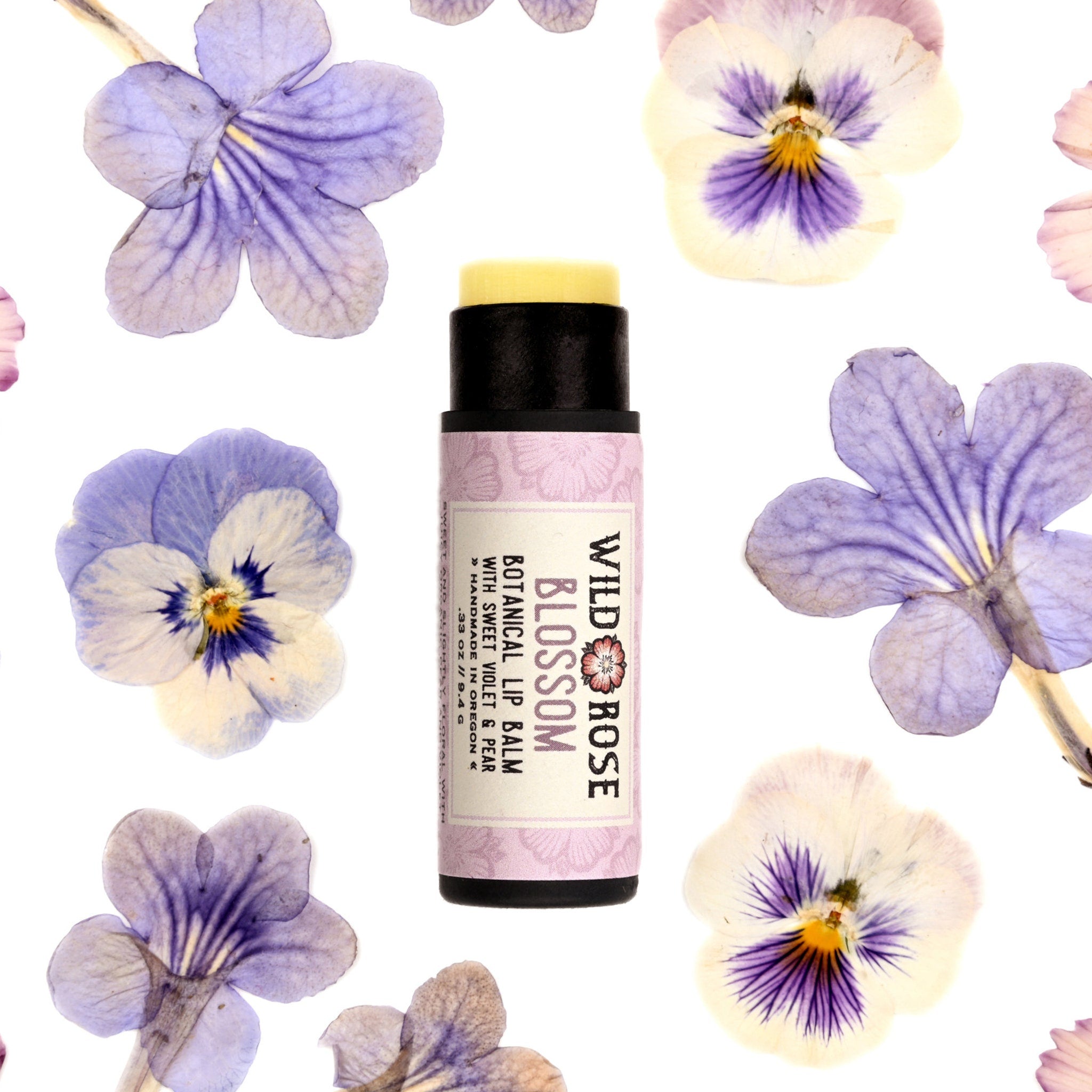 Lip balm with black tube, yellow balm, and Wild Rose Blossom label with flowers
