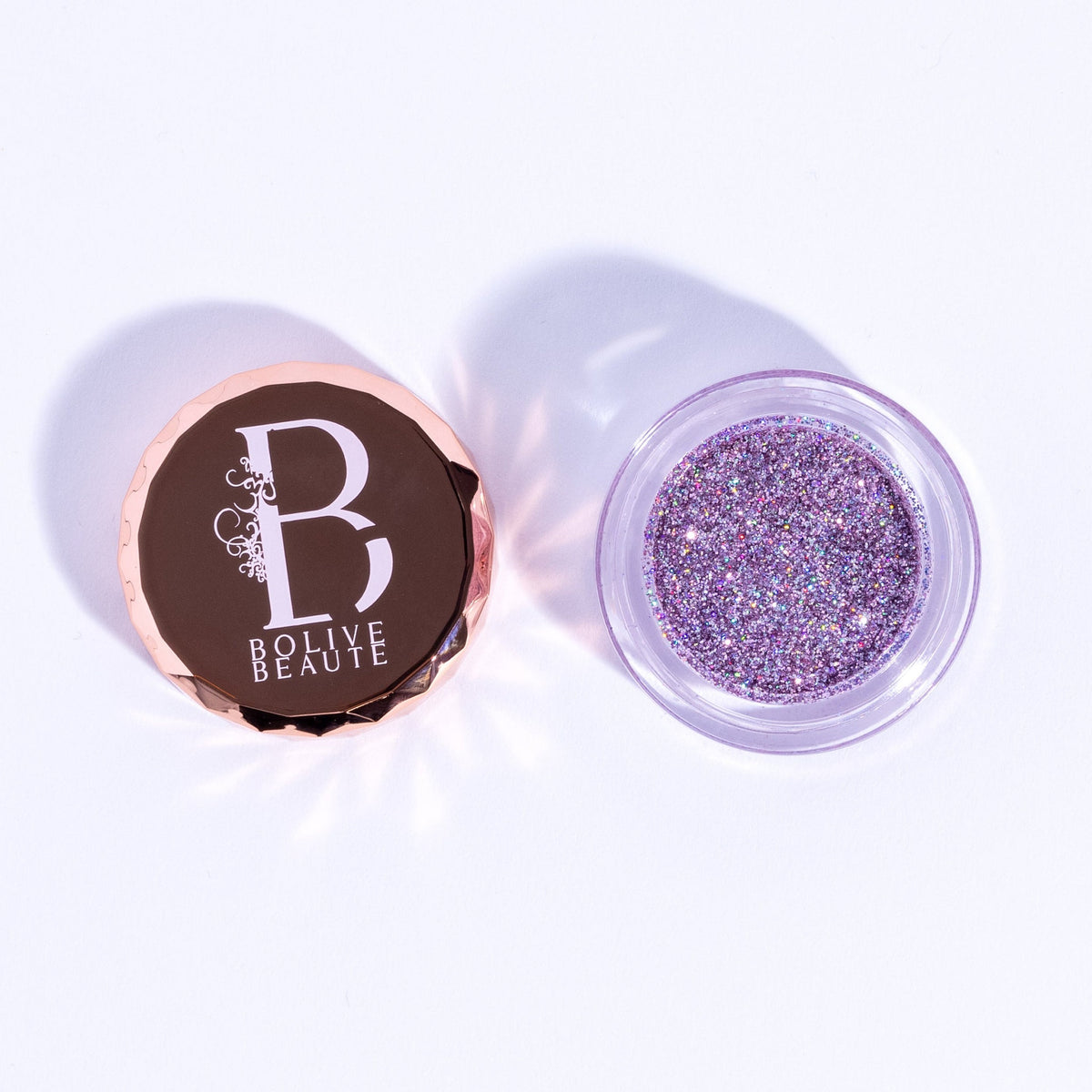 Pink and lavender fine glitter eye shadow pot with shimmer particles, displayed open on a white background