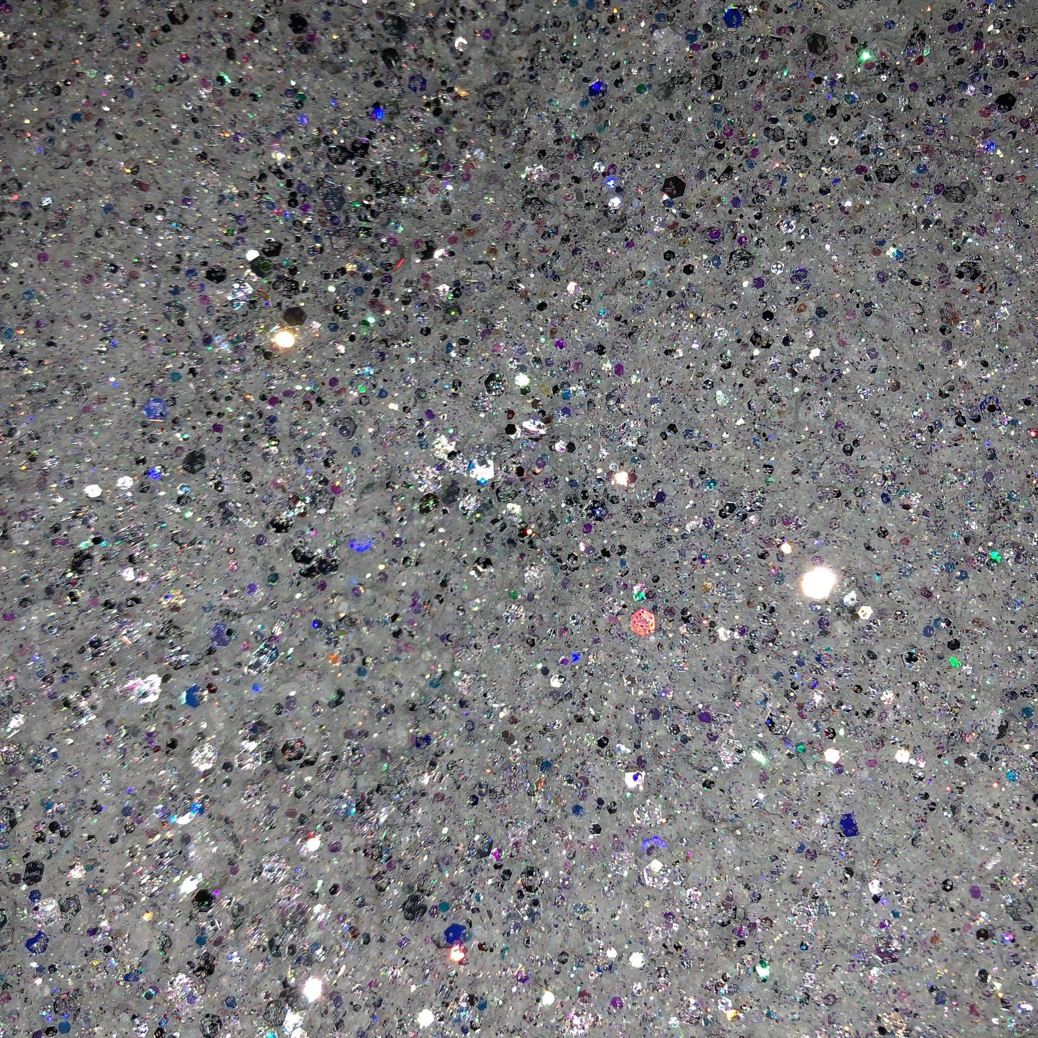 Glitter texture with white, silver, and iridescent sparkle details, close-up view