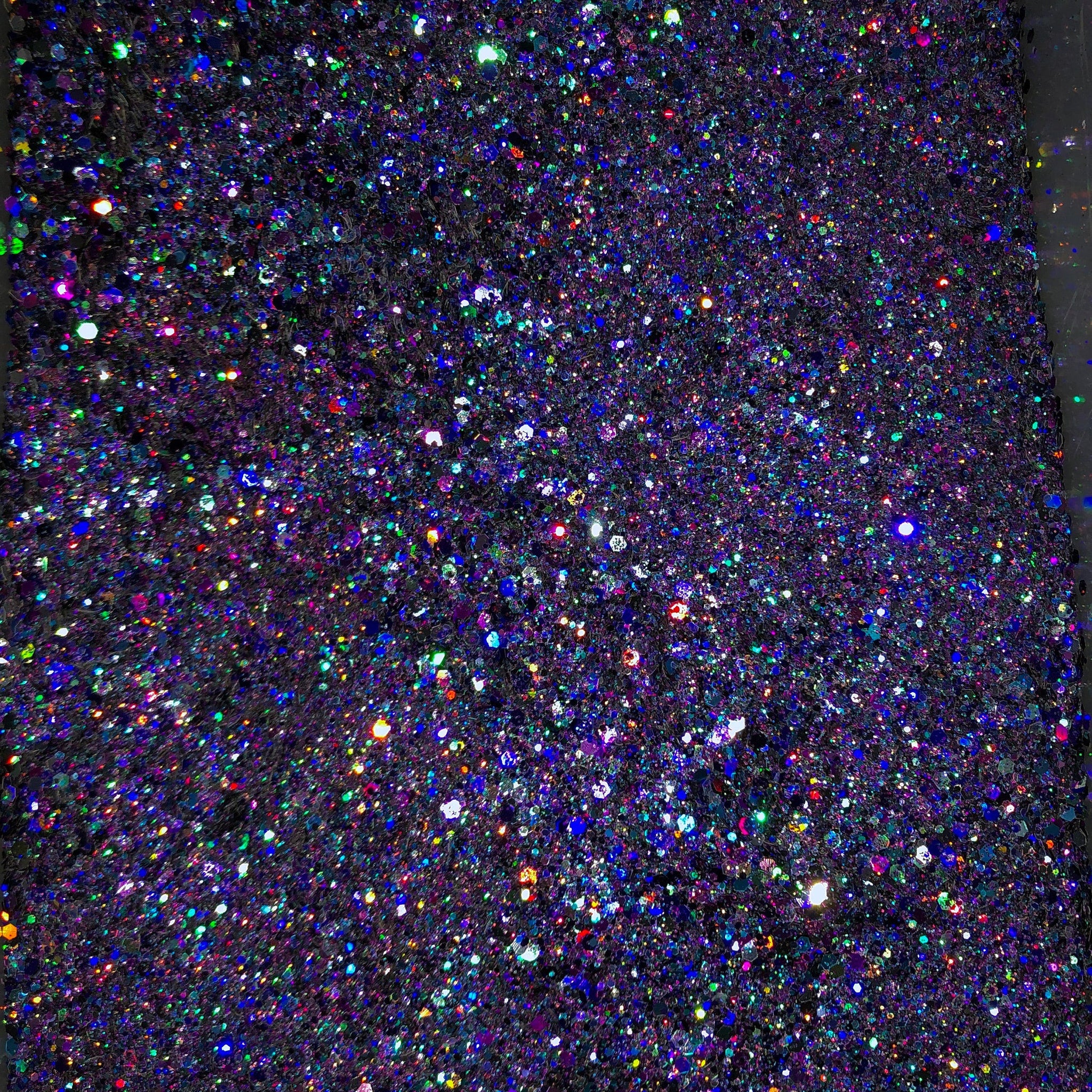 Close-up of indigo and deep purple glitter eyeshadow palette with shimmering metallic finish