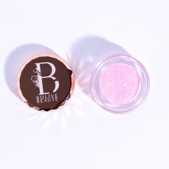 Close-up of Pink Lemonade Eye Shadow in a compact with shimmering coral-pink powder and gold flecks