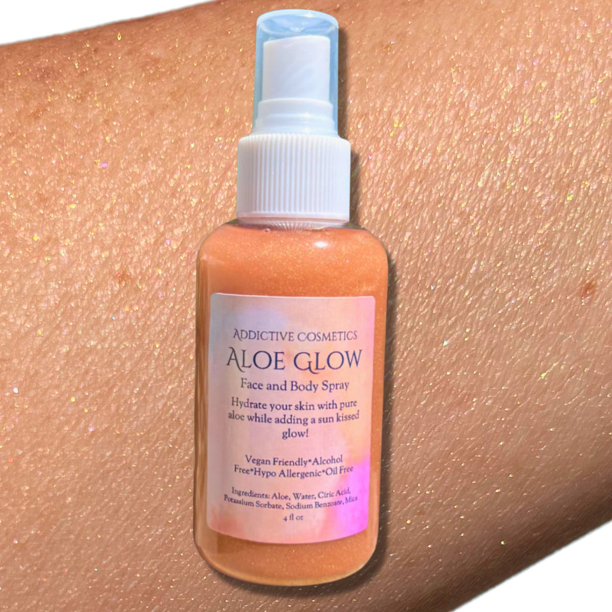 Translucent pink spray bottle of aloe glow shimmer mist with gold nozzle and minimalist label