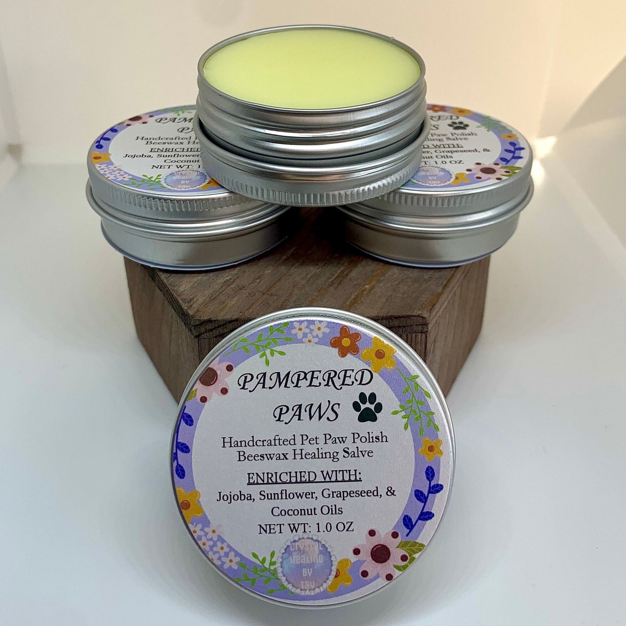 Pet paw healing salve in silver tins with floral labels, CrystalHealingbyTay brand visible