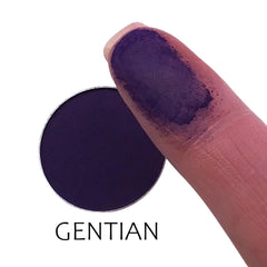 Close-up of matte gentian blue eyeshadow pan showing smooth, velvety powder texture