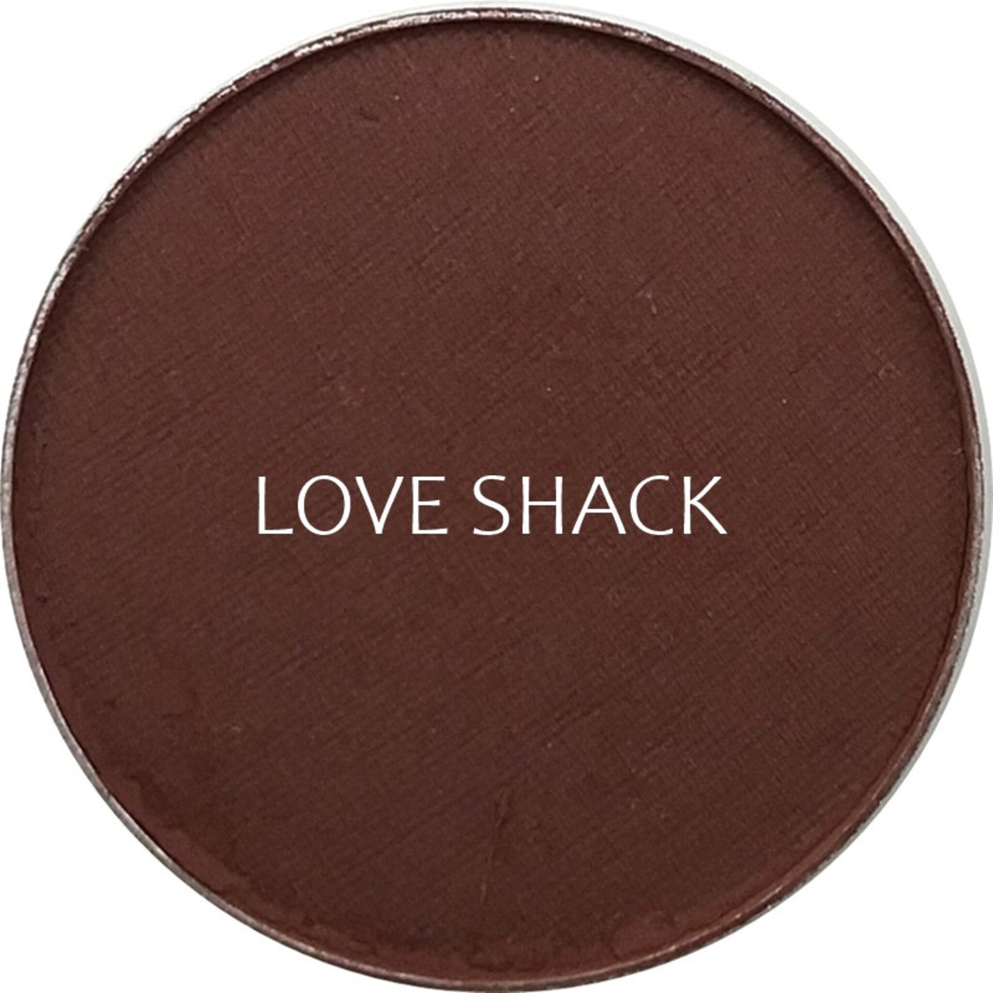 Side view of matte Love Shack eyeshadow pan showing rich taupe pigment and smooth pressed powder texture