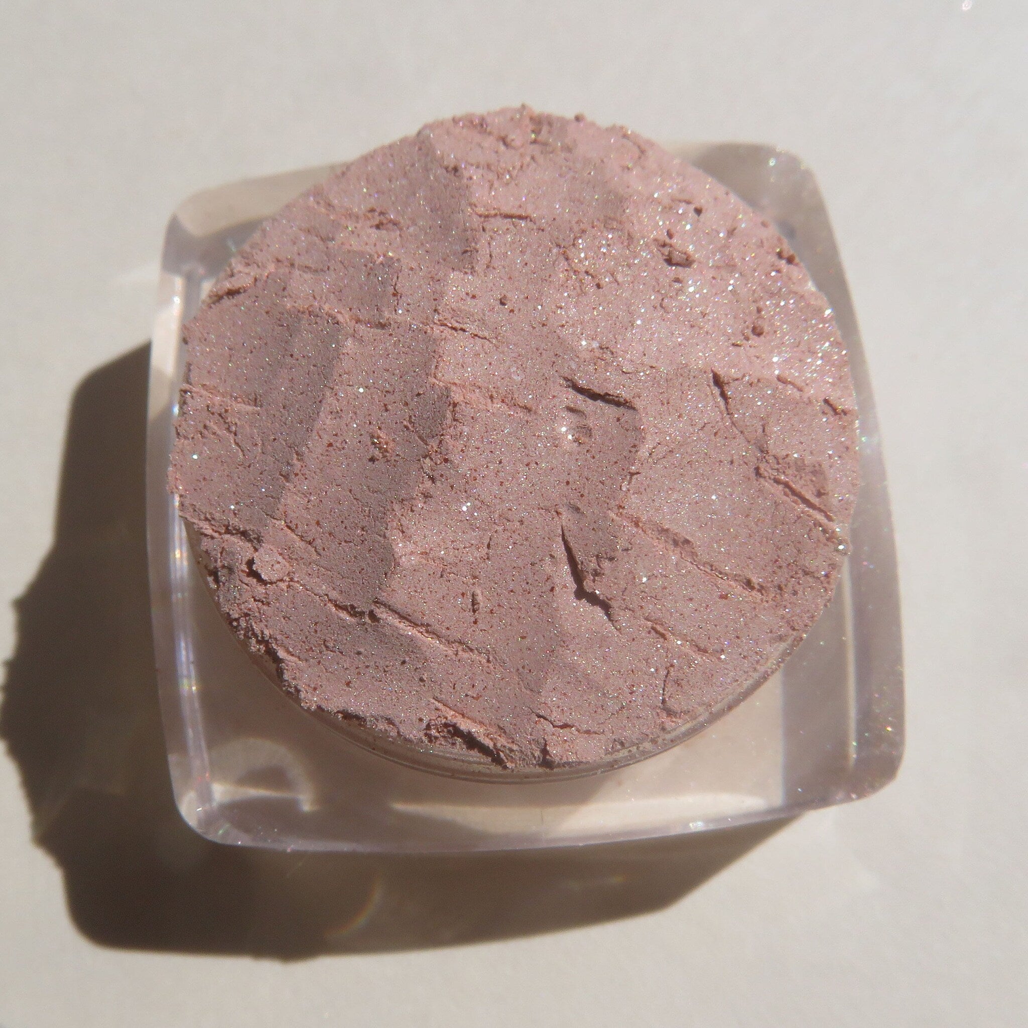 Side view of loose mineral eyeshadow in frosty golden champagne with shimmer particles catching light