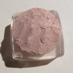 Side view of loose mineral eyeshadow in frosty golden champagne with shimmer particles catching light