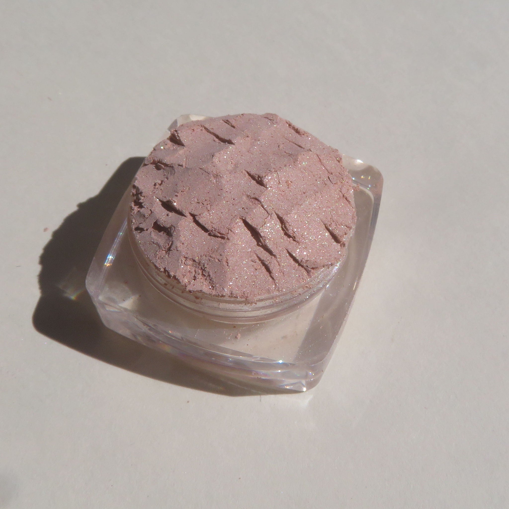 Close-up of shimmering loose mineral eyeshadow in frosty golden champagne with beige-brown undertones