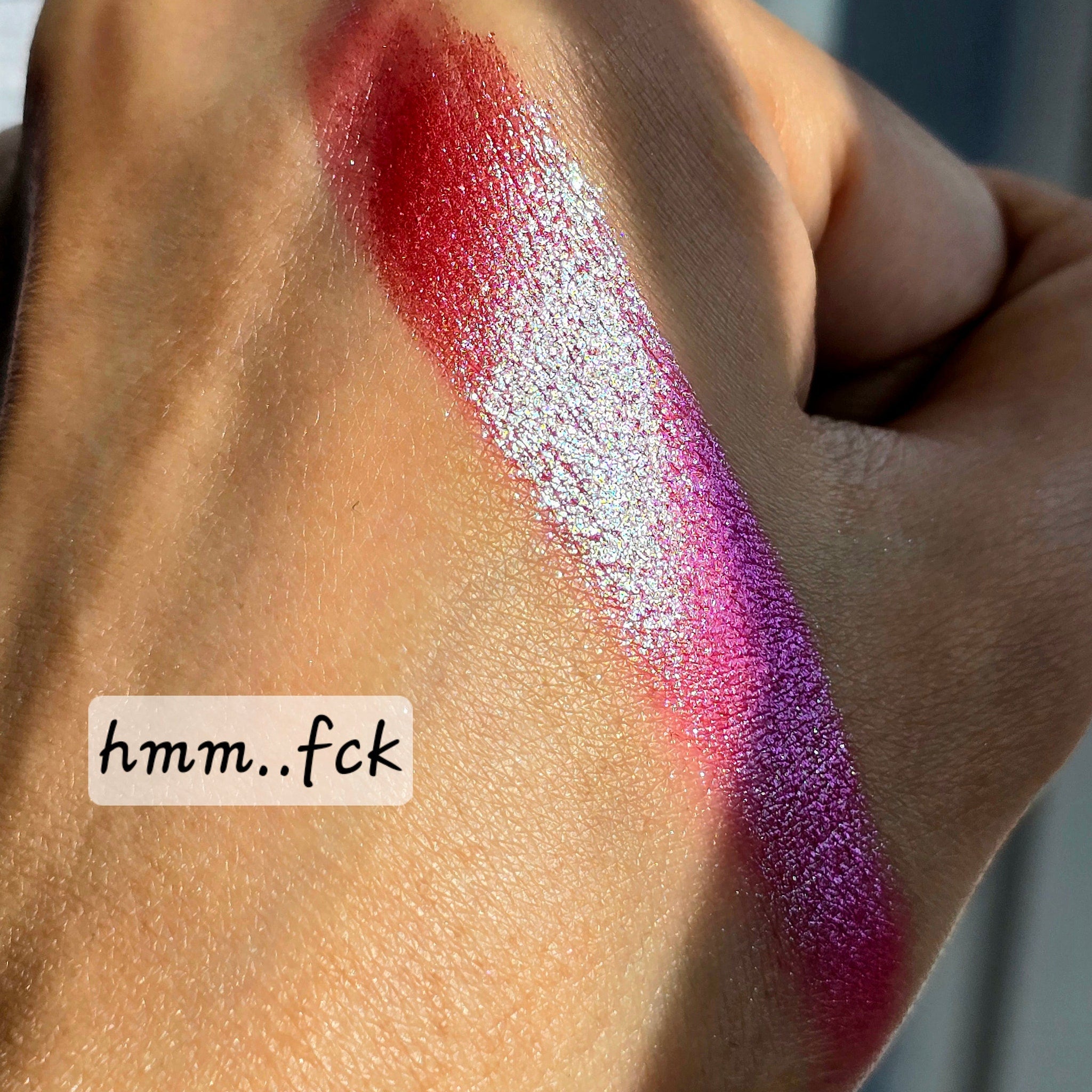 Side view of multichrome eye shadow pot showing shimmery color shift from bronze to green in angled light