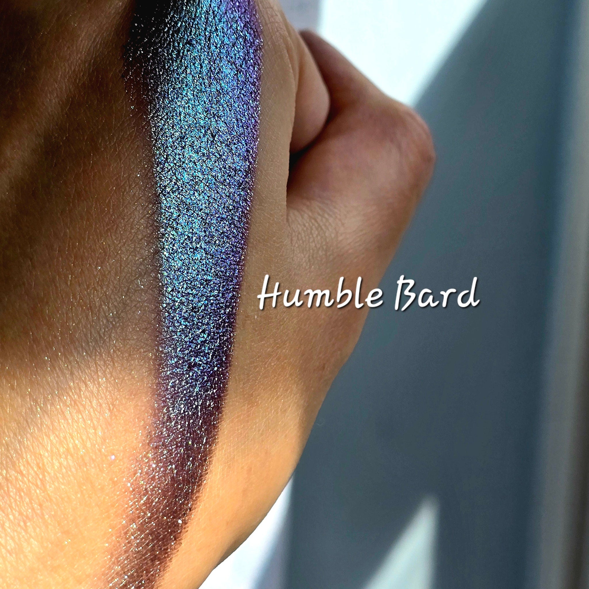 Side view of Humble Bard multichrome eyeshadow compact showing shimmery color shift from purple to green