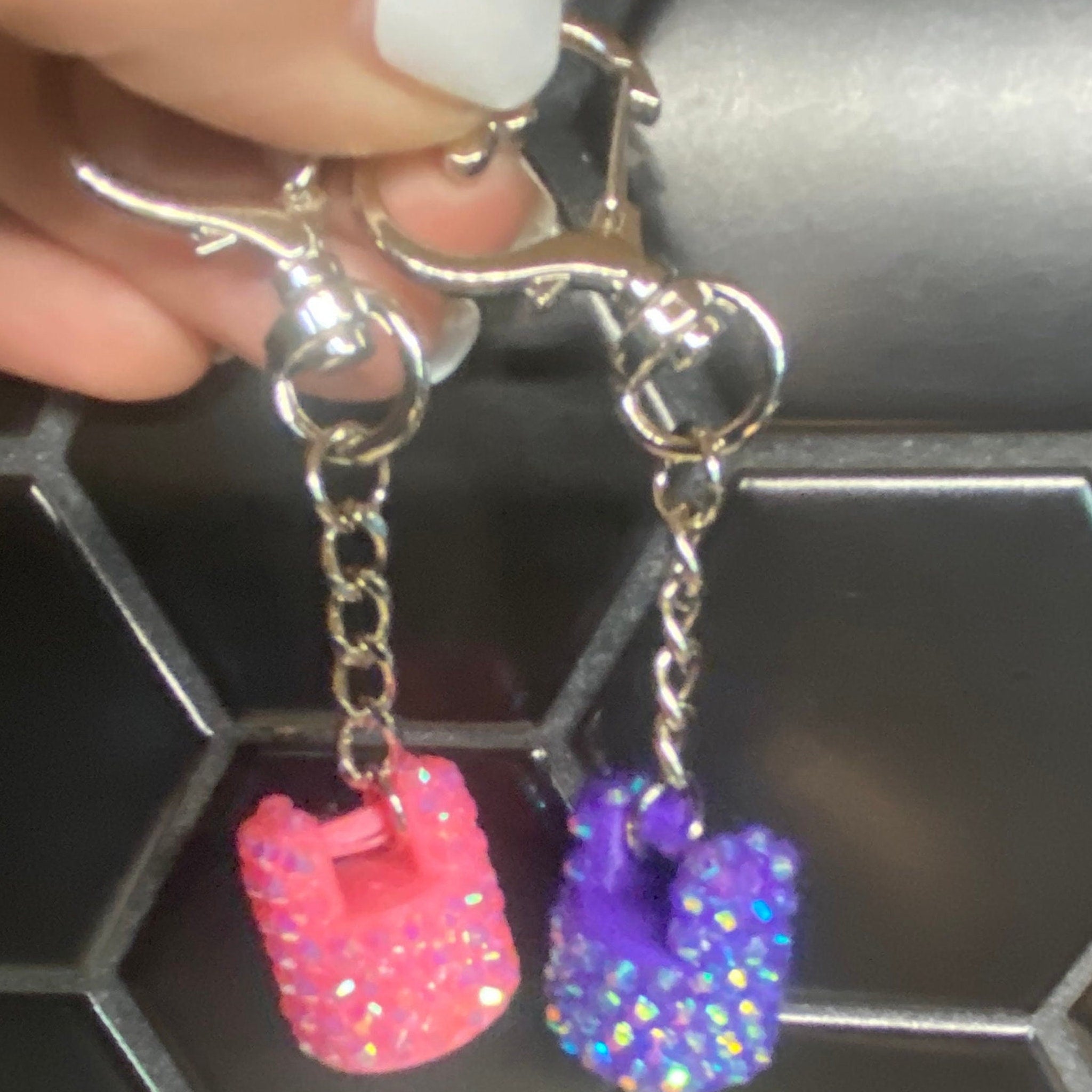 Keychain charms with pink and purple glitter, silver chain and clasp held by hand