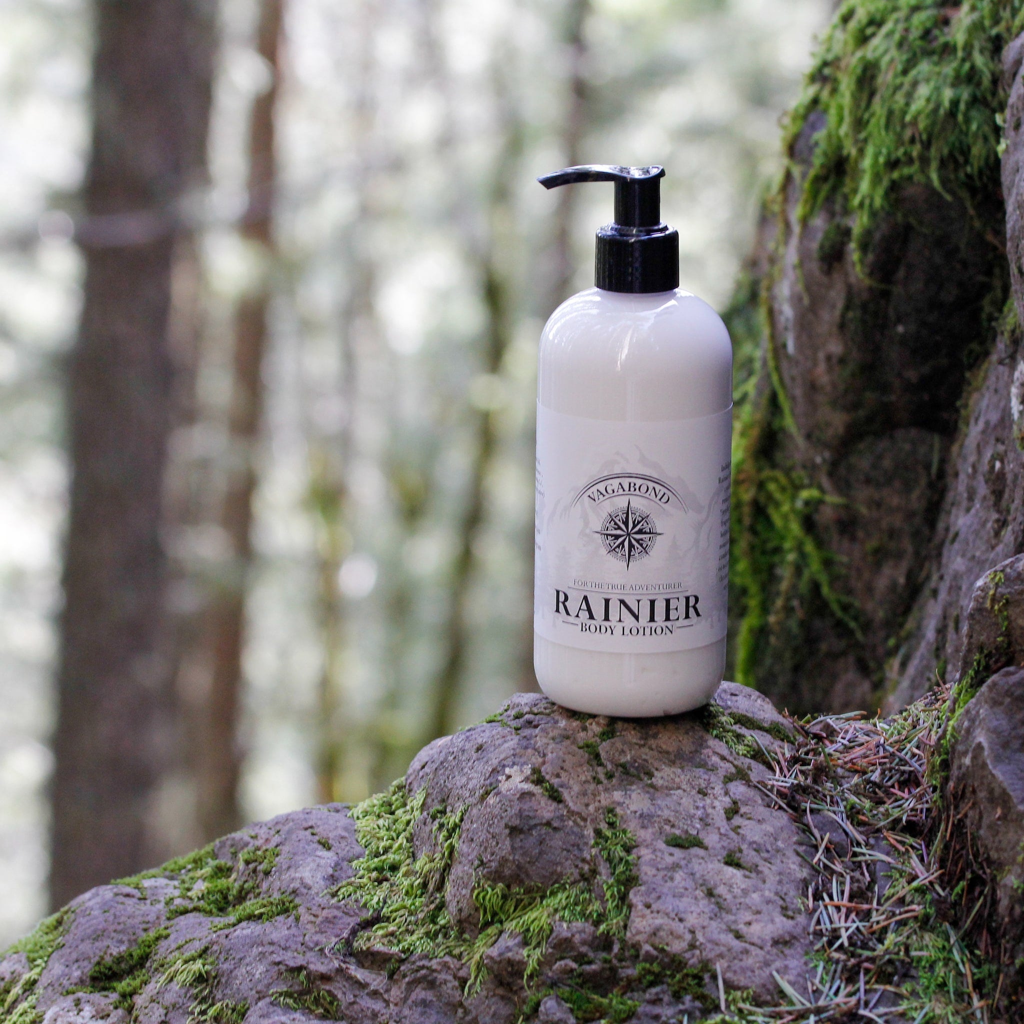 Body lotion bottle, white plastic, black pump, Vagabond Rainier label on rock in forest