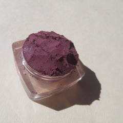 Side view of dark purple shimmer loose mineral eyeshadow in eco-friendly packaging, showcasing vibrant pigment dispersion