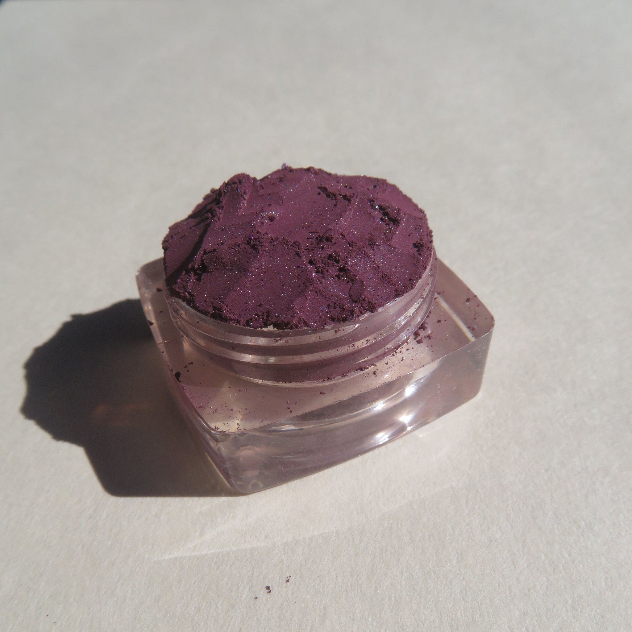 Open compact showing dark purple shimmer vegan mineral eye shadow with eco-friendly packaging