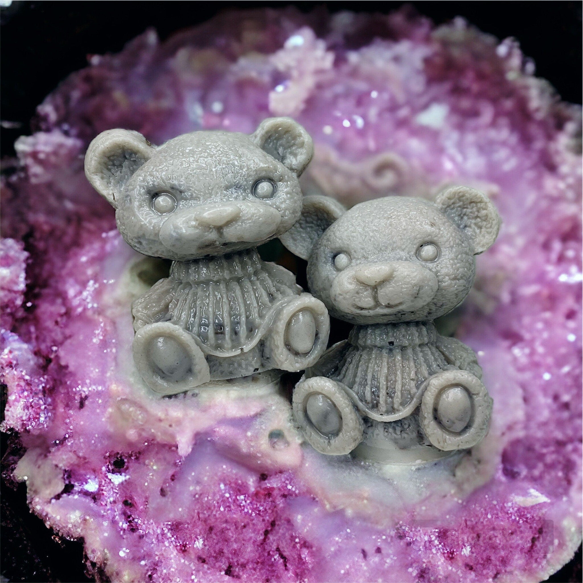 Gray teddy bear figurines with detailed texture and seated pose on purple surface