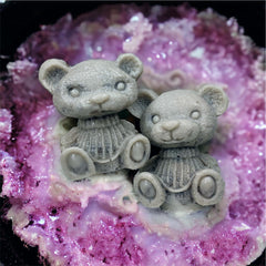 Gray teddy bear figurines with detailed texture and seated pose on purple surface