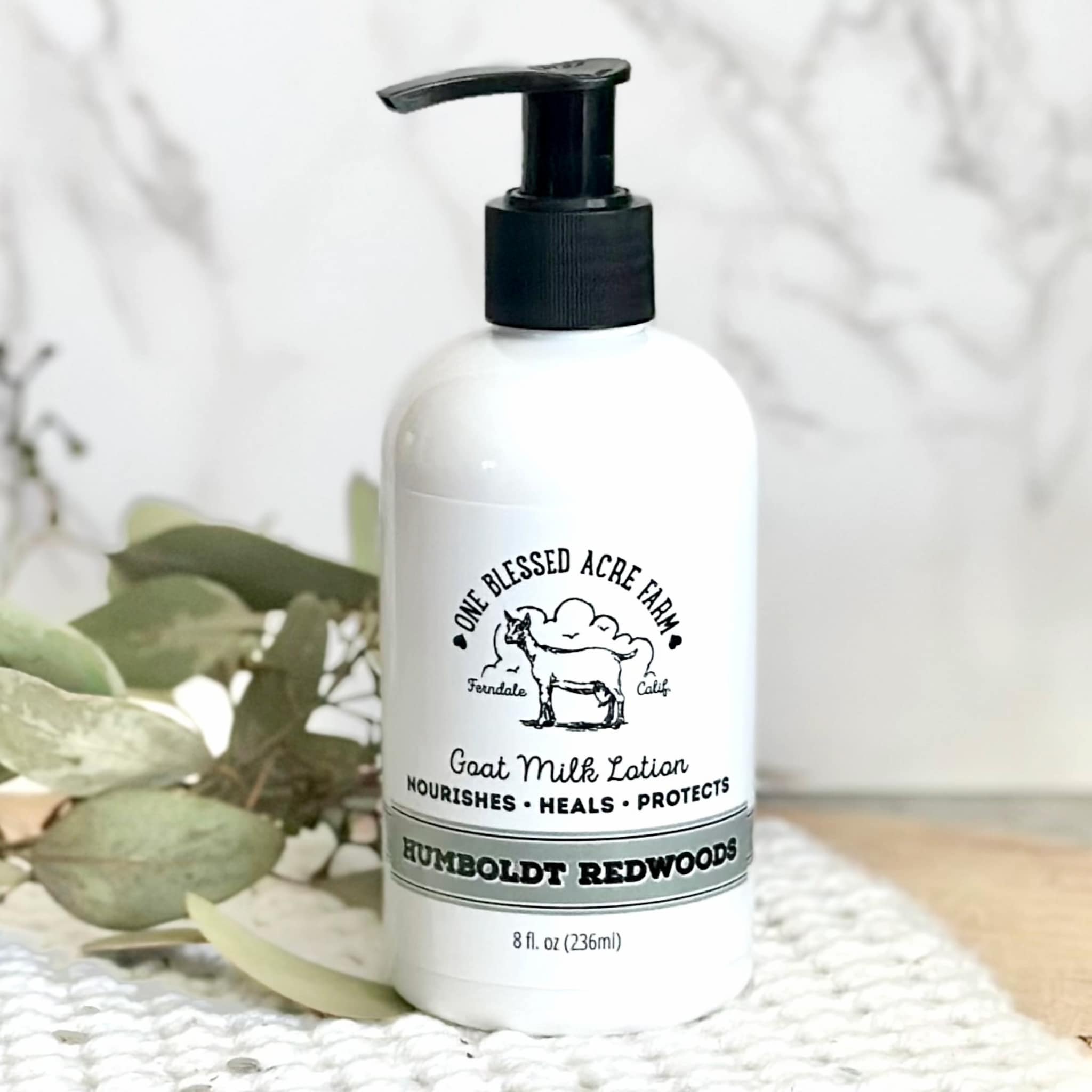 Goat milk lotion bottle with black pump, white label, and One Blessed Acre Farm text