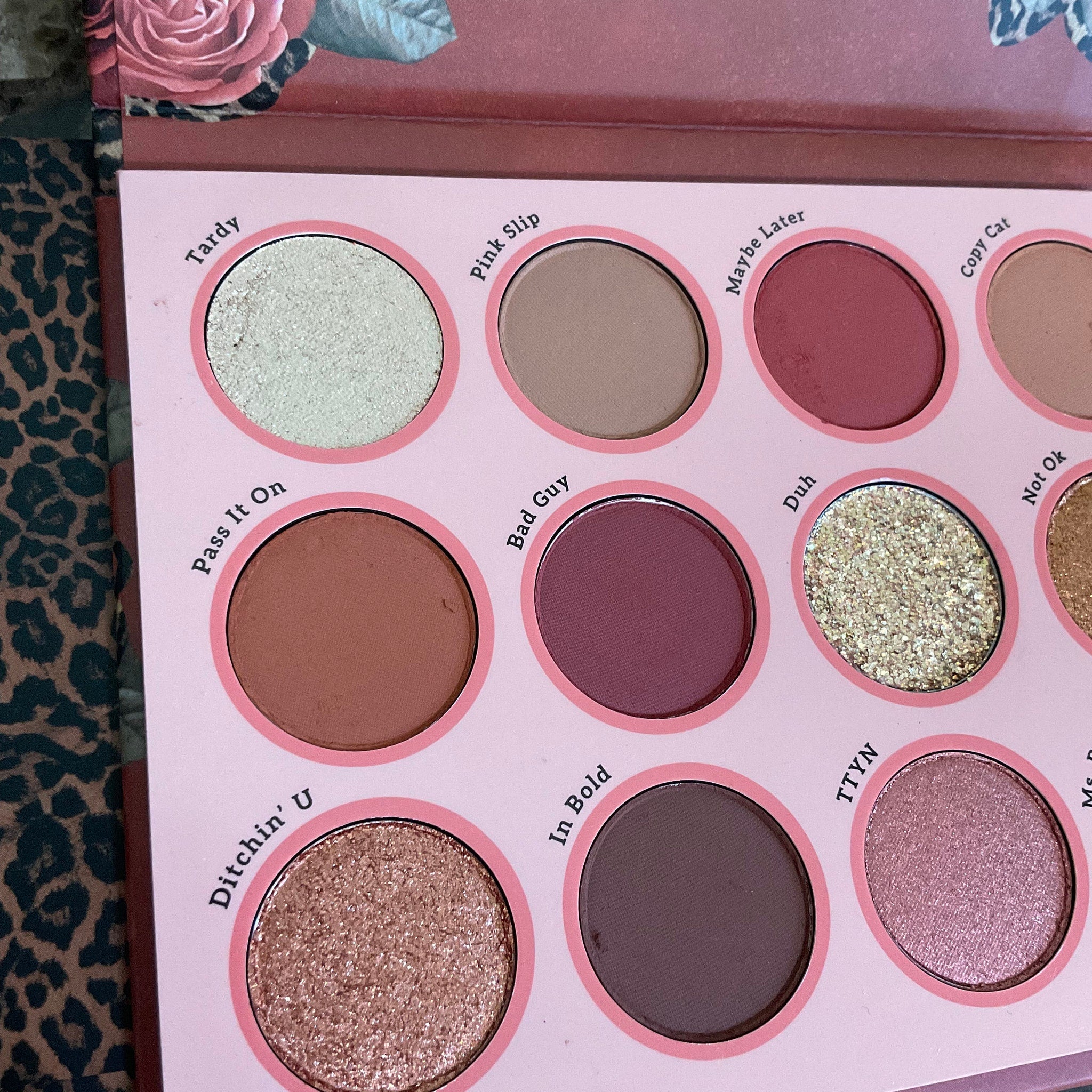 Hand applying shimmery taupe eyeshadow from palette with fingertip onto eyelid