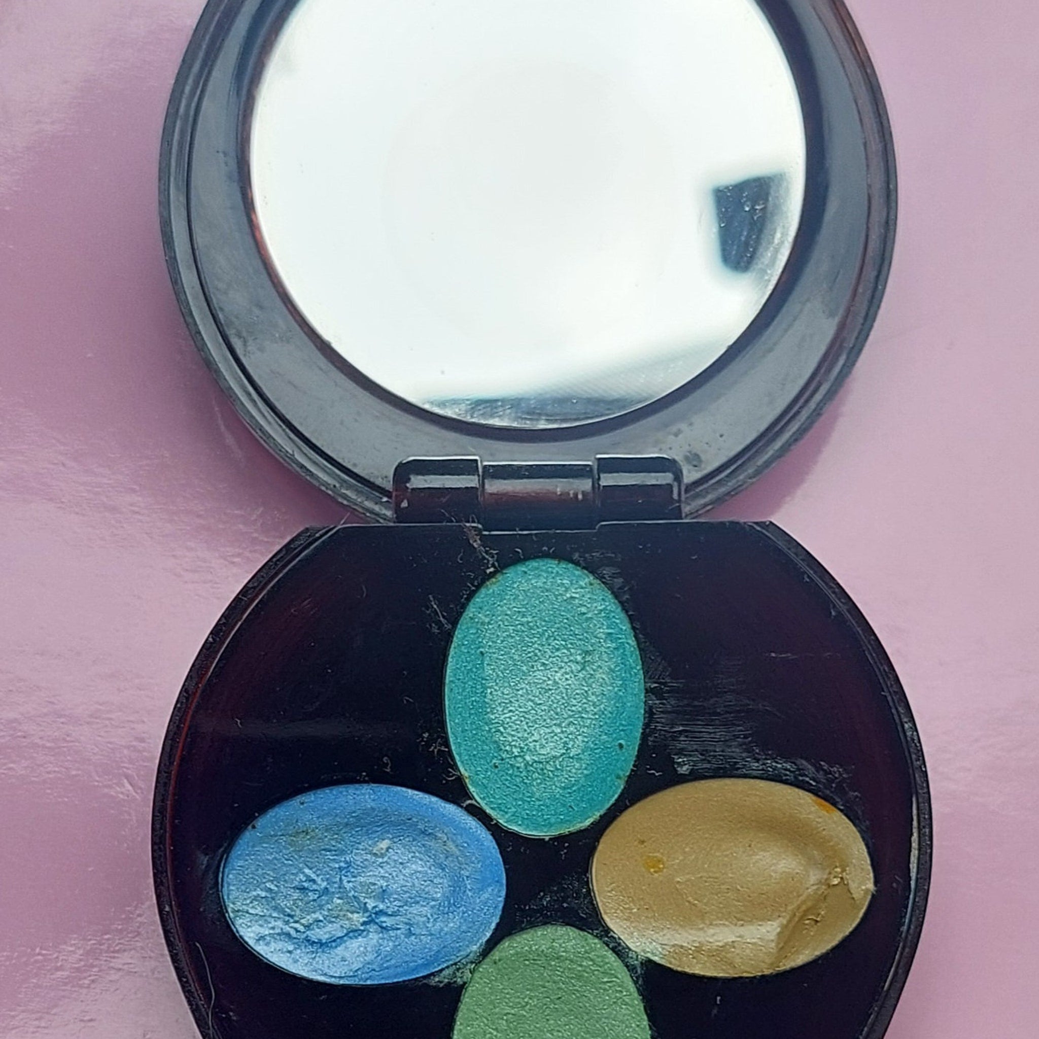 Hand applying shimmery bronze cream eyeshadow from vintage Avon compact with mirror