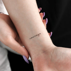 Temporary tattoo with black script "courage" on wrist, skin tone, hand with purple nails