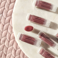 Lip balms, elderberry tinted, clear tubes, Basswood Beauty branding visible