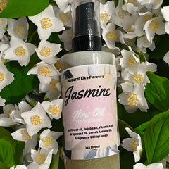 Jasmine Glow Oil bottle with pink label, glitter, and white flowers background.