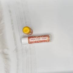 Lip balm tubes and container with white and glittery brown labels, yellow balm visible