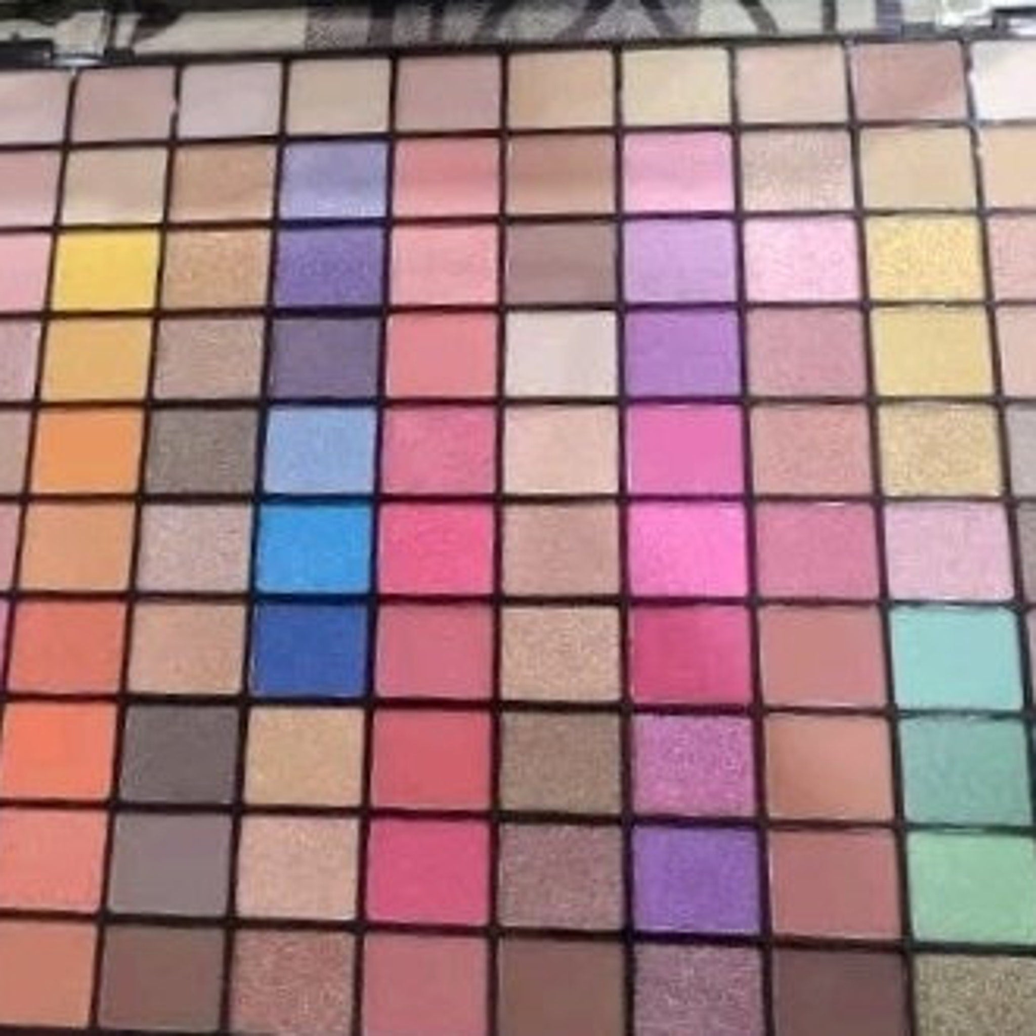 Eyeshadow palette with multiple colorful squares in various shades and textures