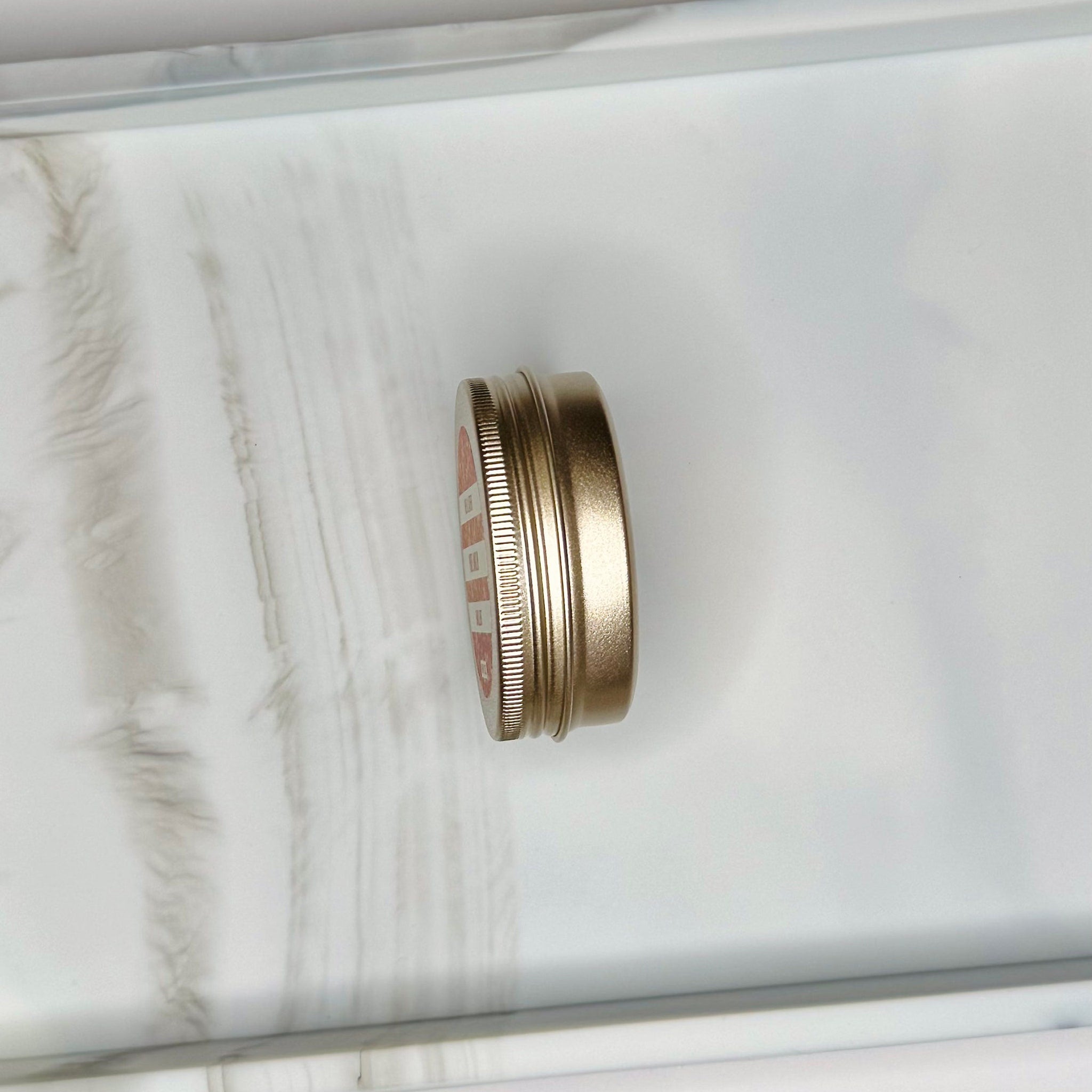 Tin container, metallic gold color, ribbed side, with red and white text on the top lid