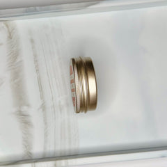 Tin container, metallic gold color, ribbed side, with red and white text on the top lid
