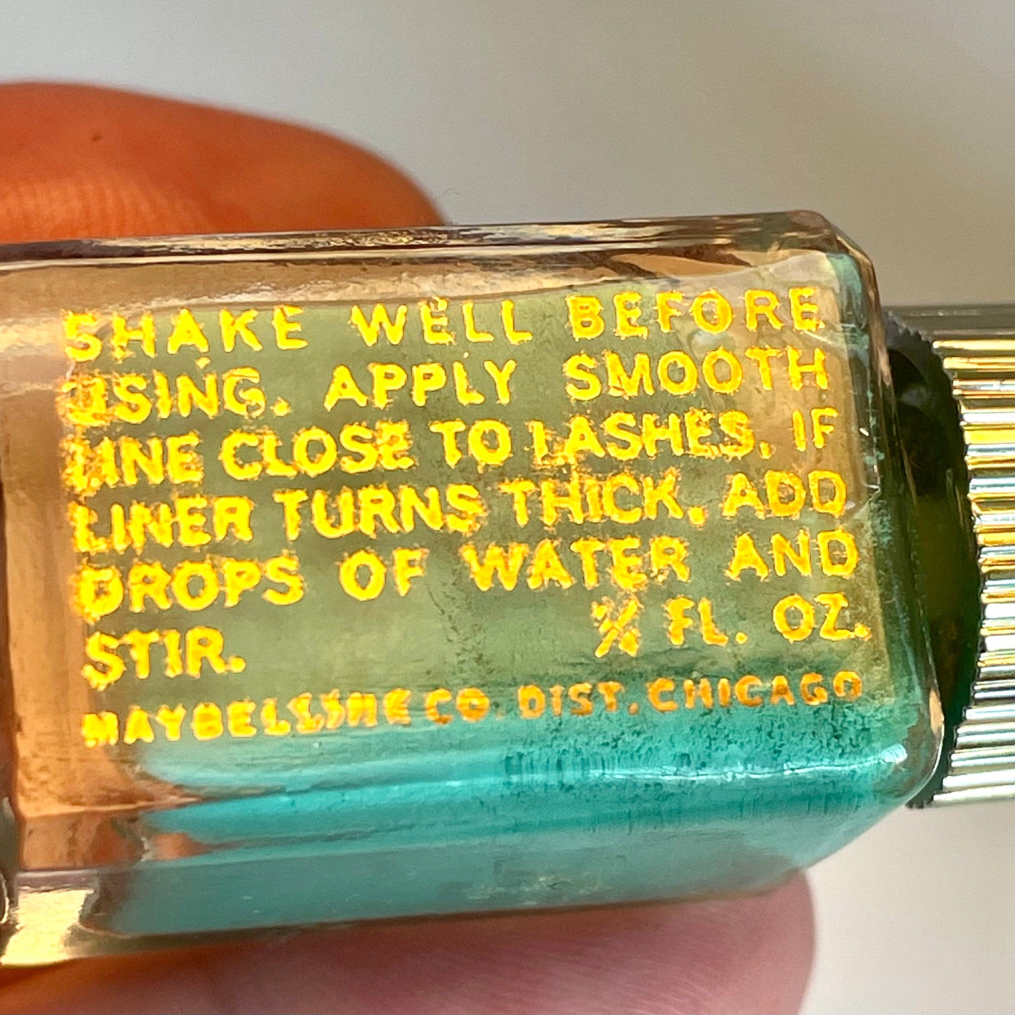 Close-up of the golden spire lid and glass bottle showcasing the vintage 1960 Maybelline green fluid eyeliner