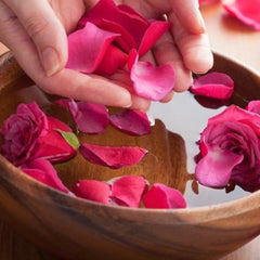 Rose petals floating in wooden bowl with water, red and pink petals, spa scene