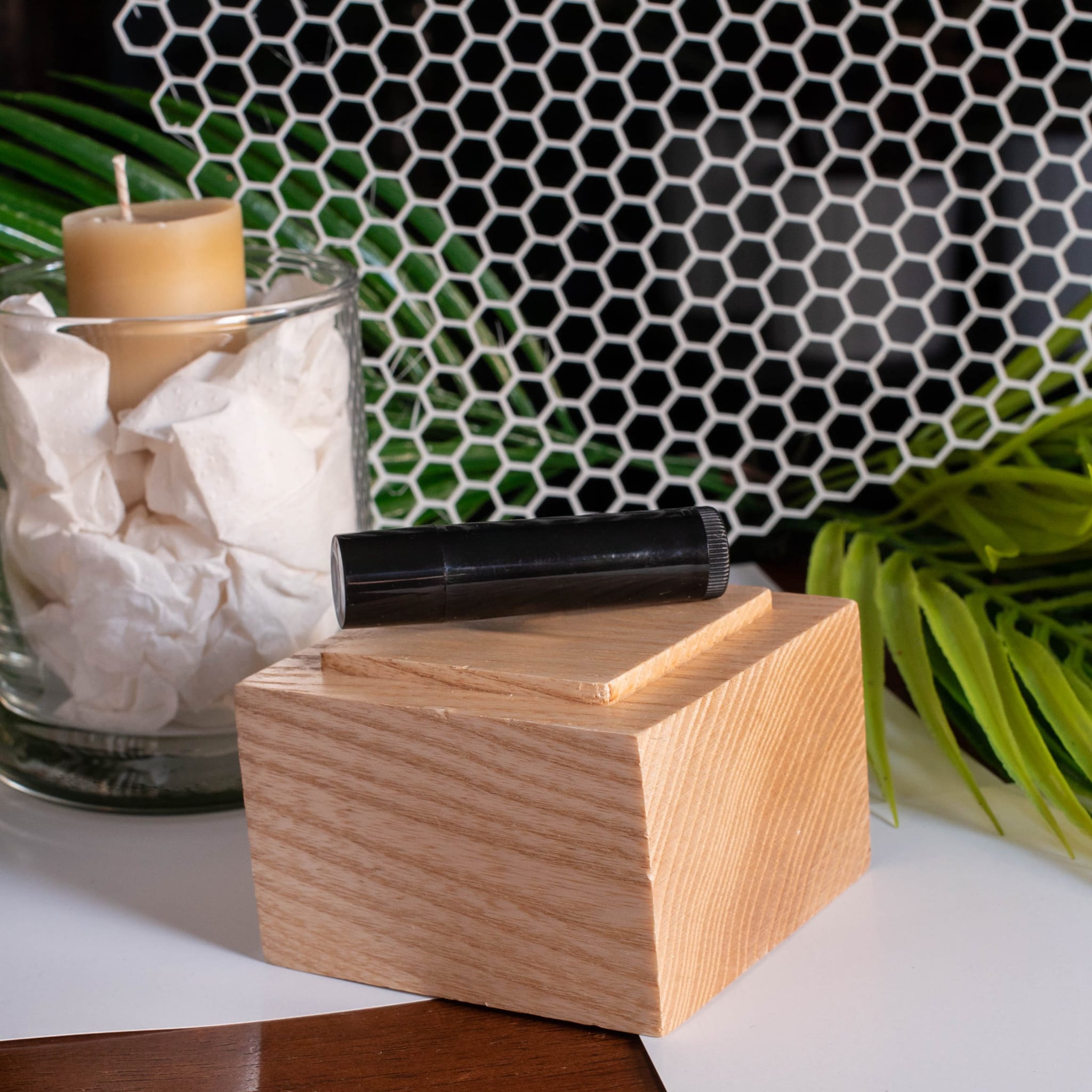 Black cylindrical object on wooden block, light brown wood grain, white background