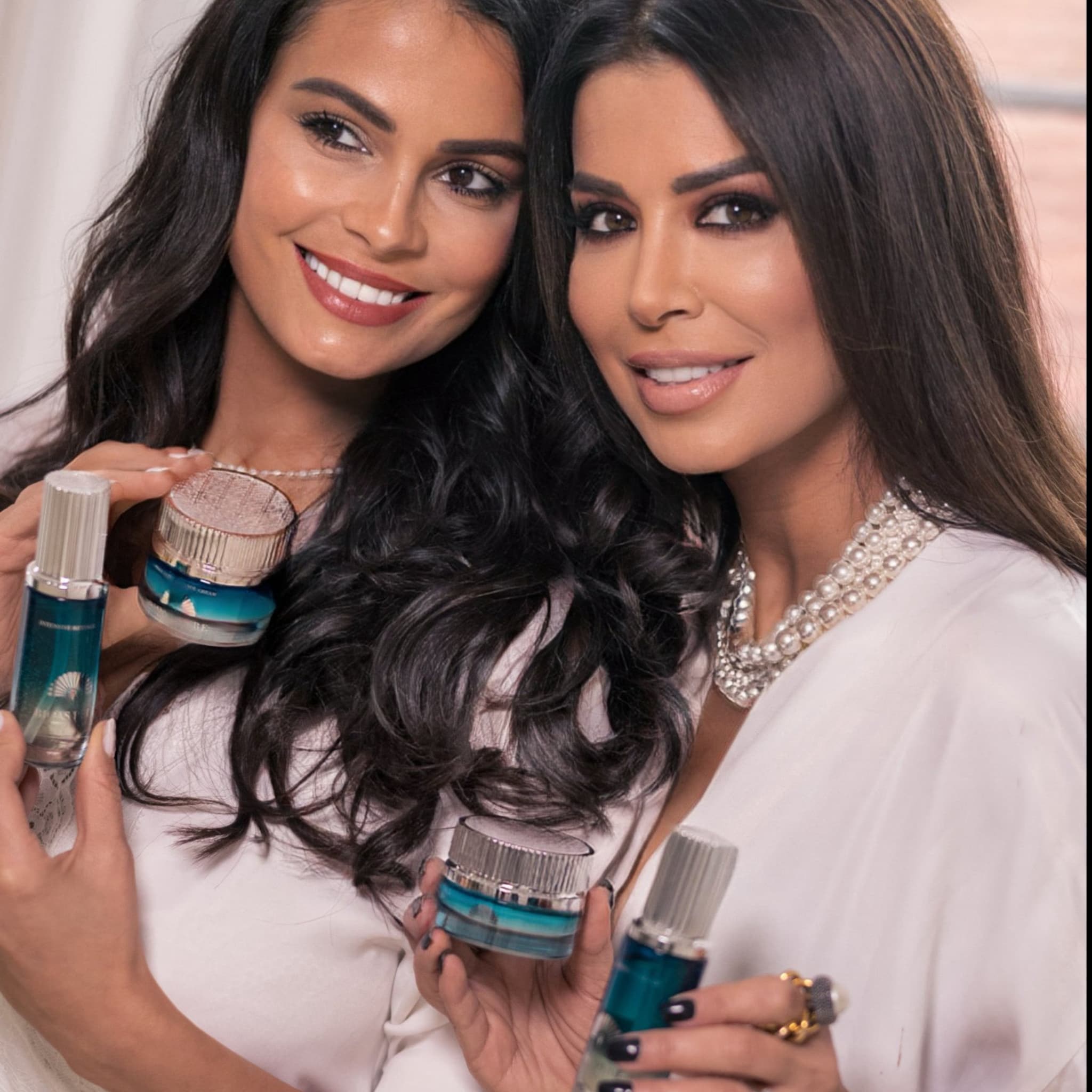 Skincare products with blue and silver packaging held by women in white outfits
