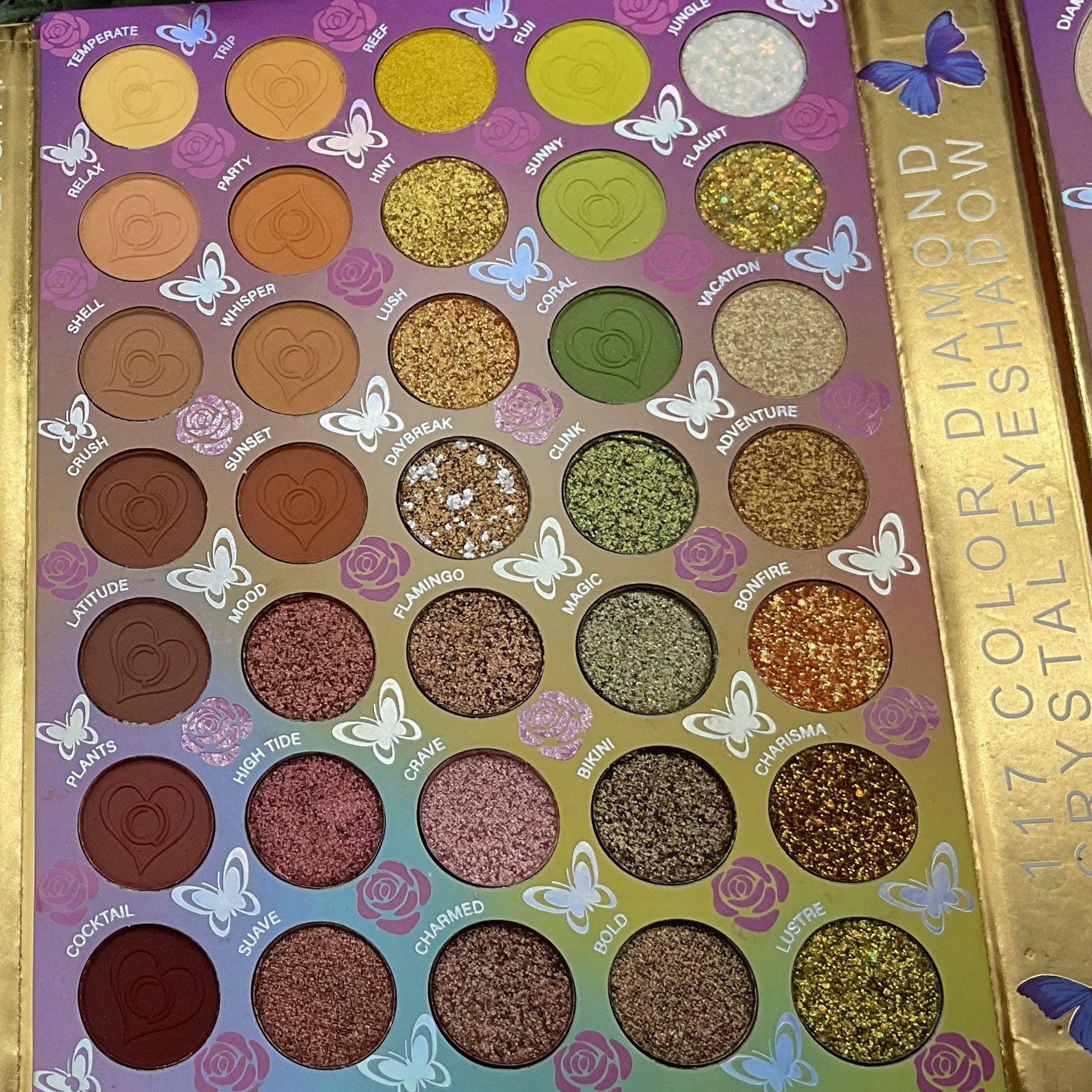 Eyeshadow palette with various colors, heart-shaped design, and butterfly accents, "117 Color Diamond Eyeshadow" text visible