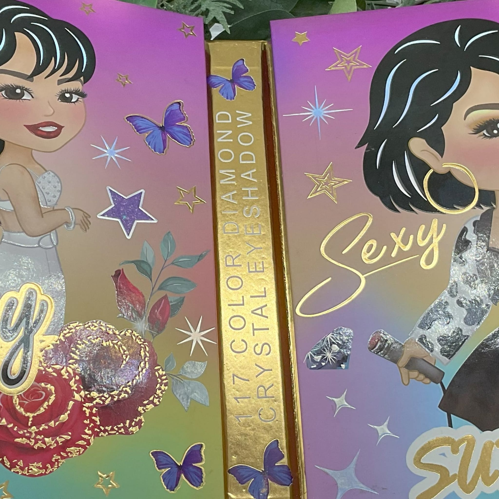 Eyeshadow palette with gold lettering, butterfly and star accents, and cartoon illustration