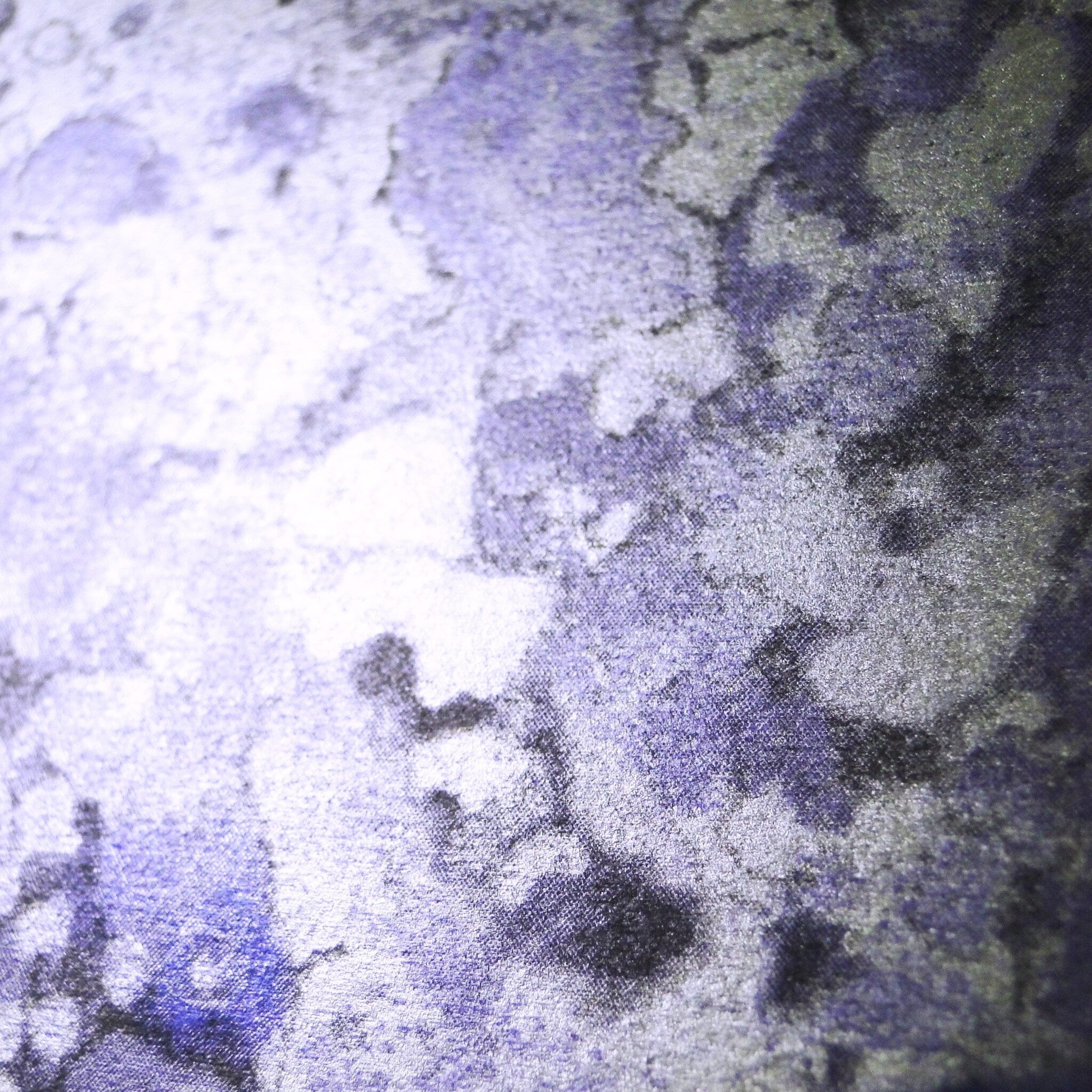 Close-up of shimmering purple and silver marbleized eyeshadow pans in sleek black palette