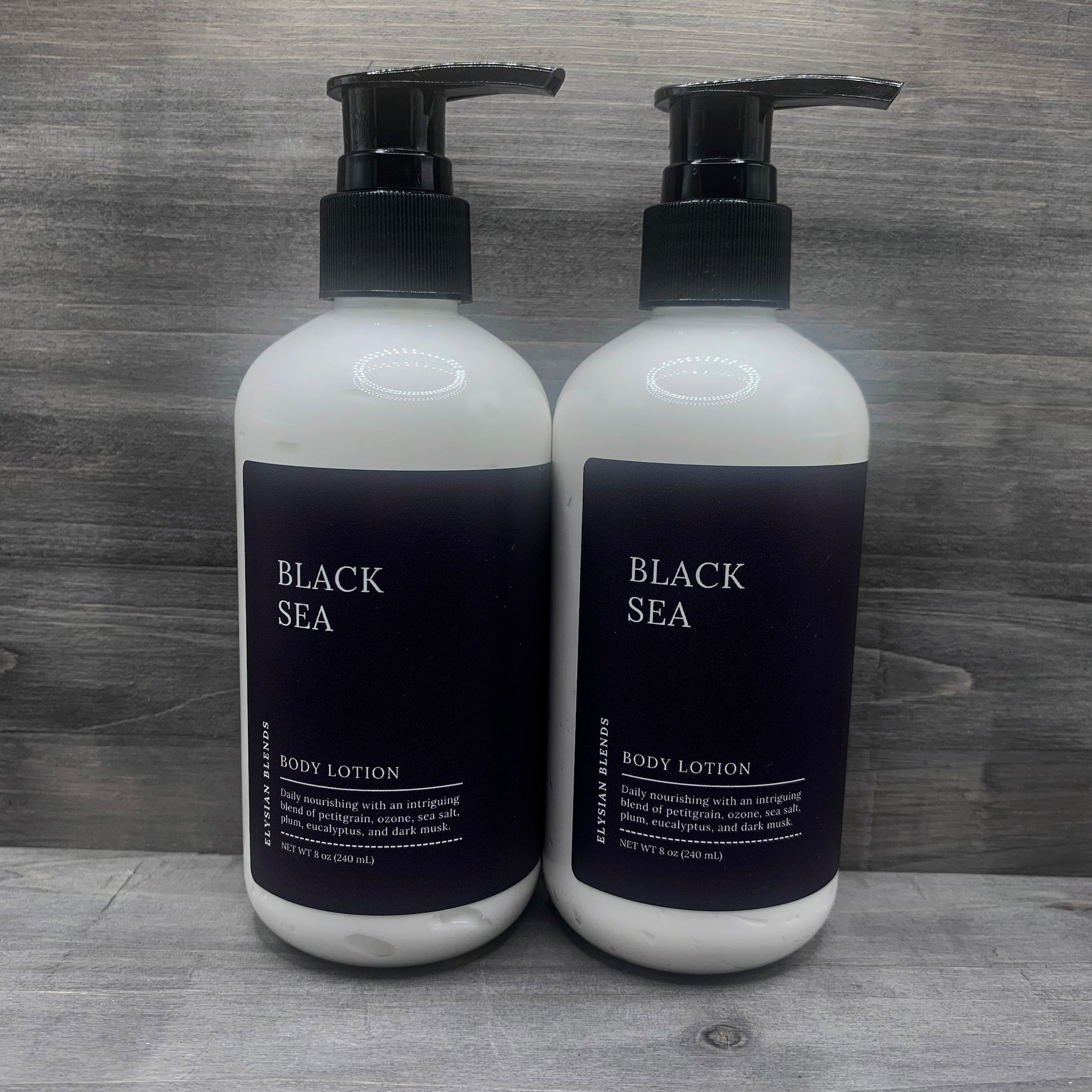 Body lotion bottles, white and black with pump, "BLACK SEA" text visible, by Elysian Blends