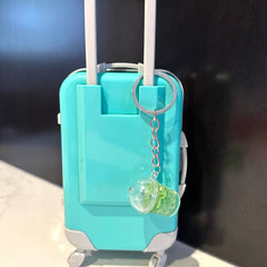 Miniature turquoise suitcase with white handle and silver keychain with drink charm