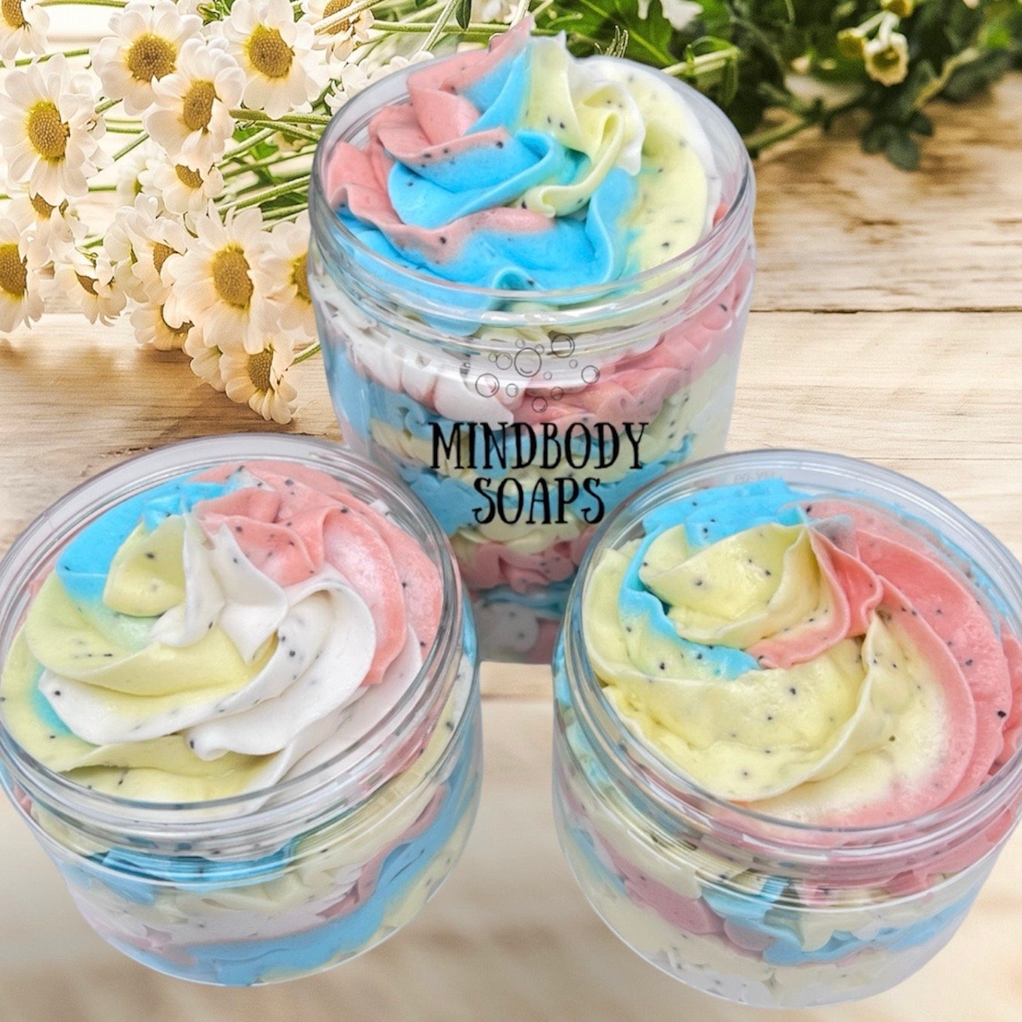 Body butter sugar scrub with colorful swirls, clear jars, and Mindbody Soaps text
