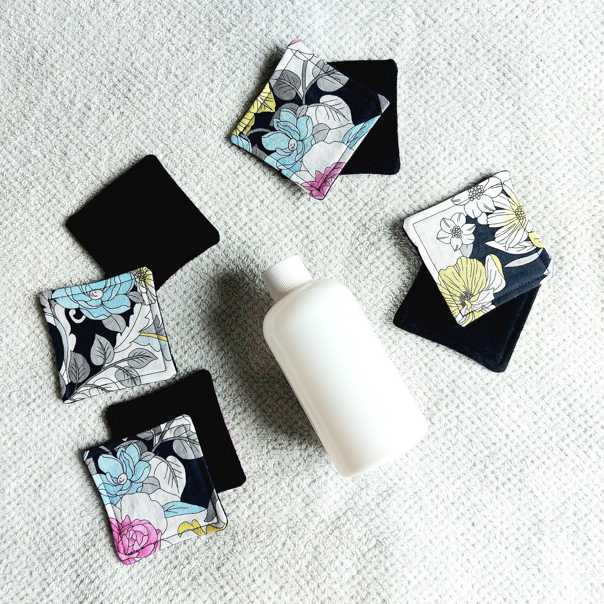 Makeup remover pads, floral pattern fabric, black backing, on white surface