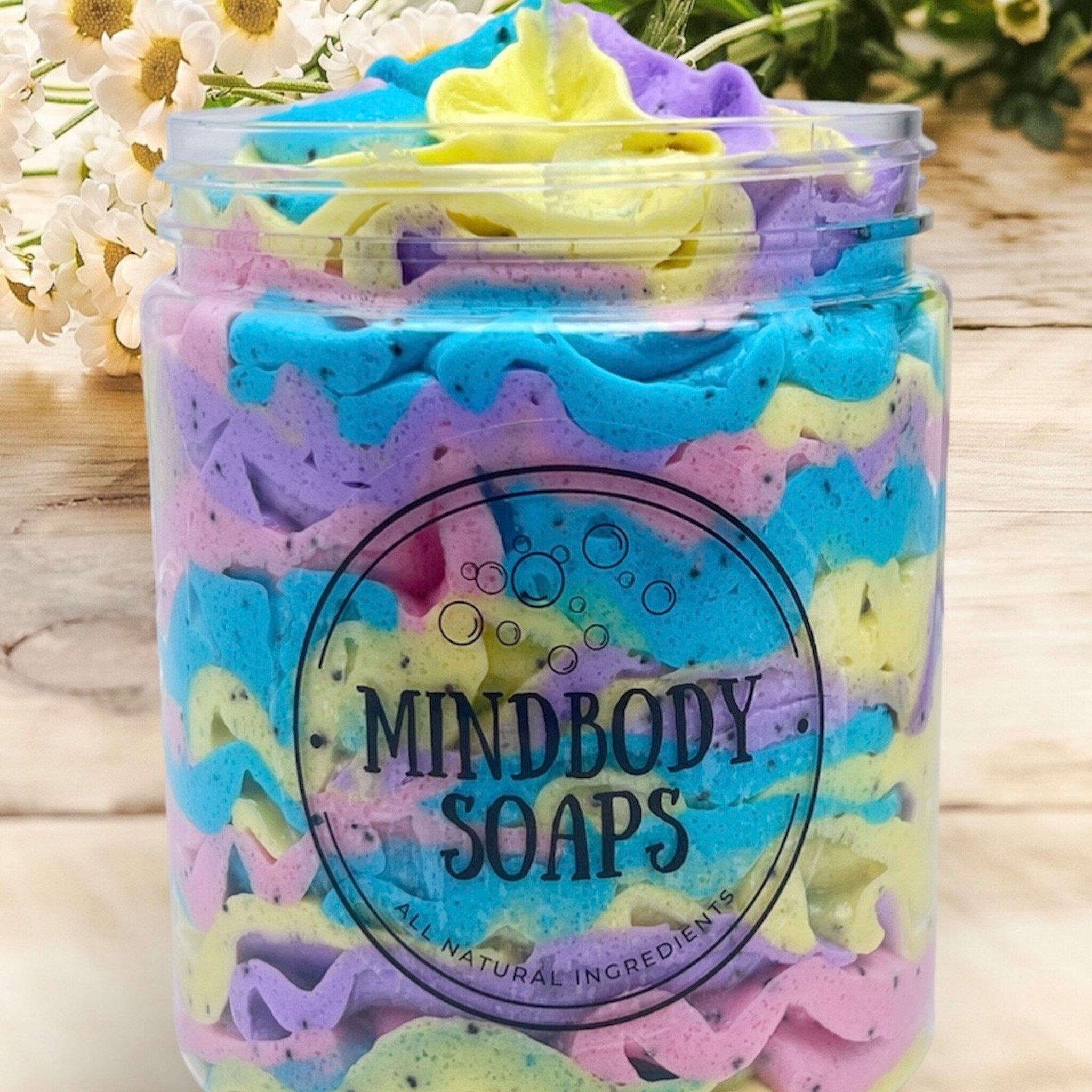 Whipped soap in jar with blue, purple, yellow swirls, Mindbody Soaps brand visible, all natural ingredients