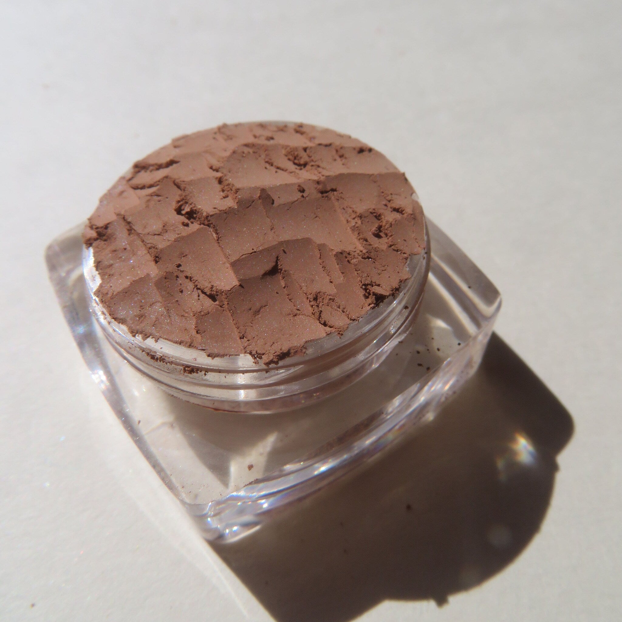 Side view of matte brown loose mineral eyeshadow in eco-friendly packaging with sifter top