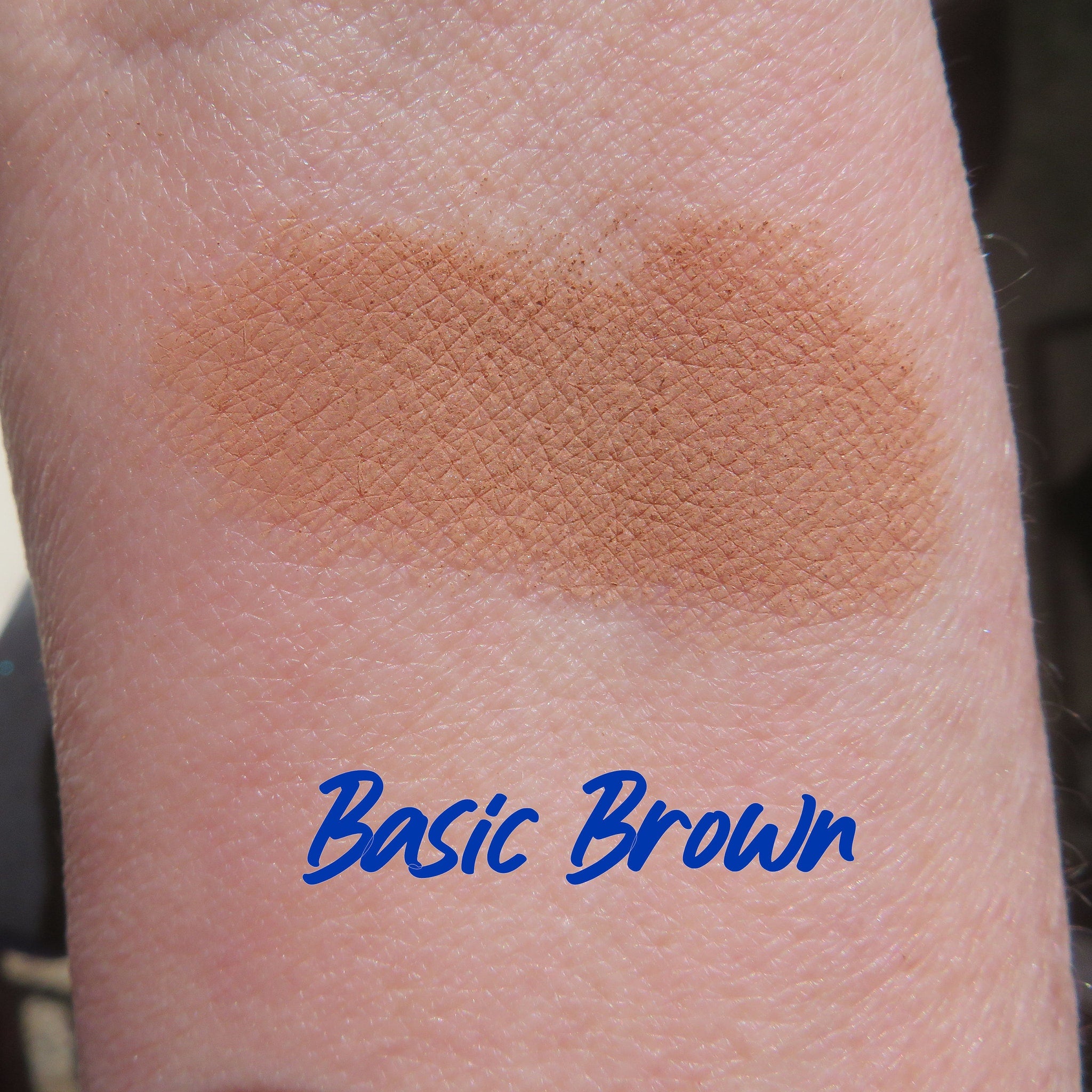 Side view of matte brown loose mineral eyeshadow powder spilling from eco-friendly container onto surface