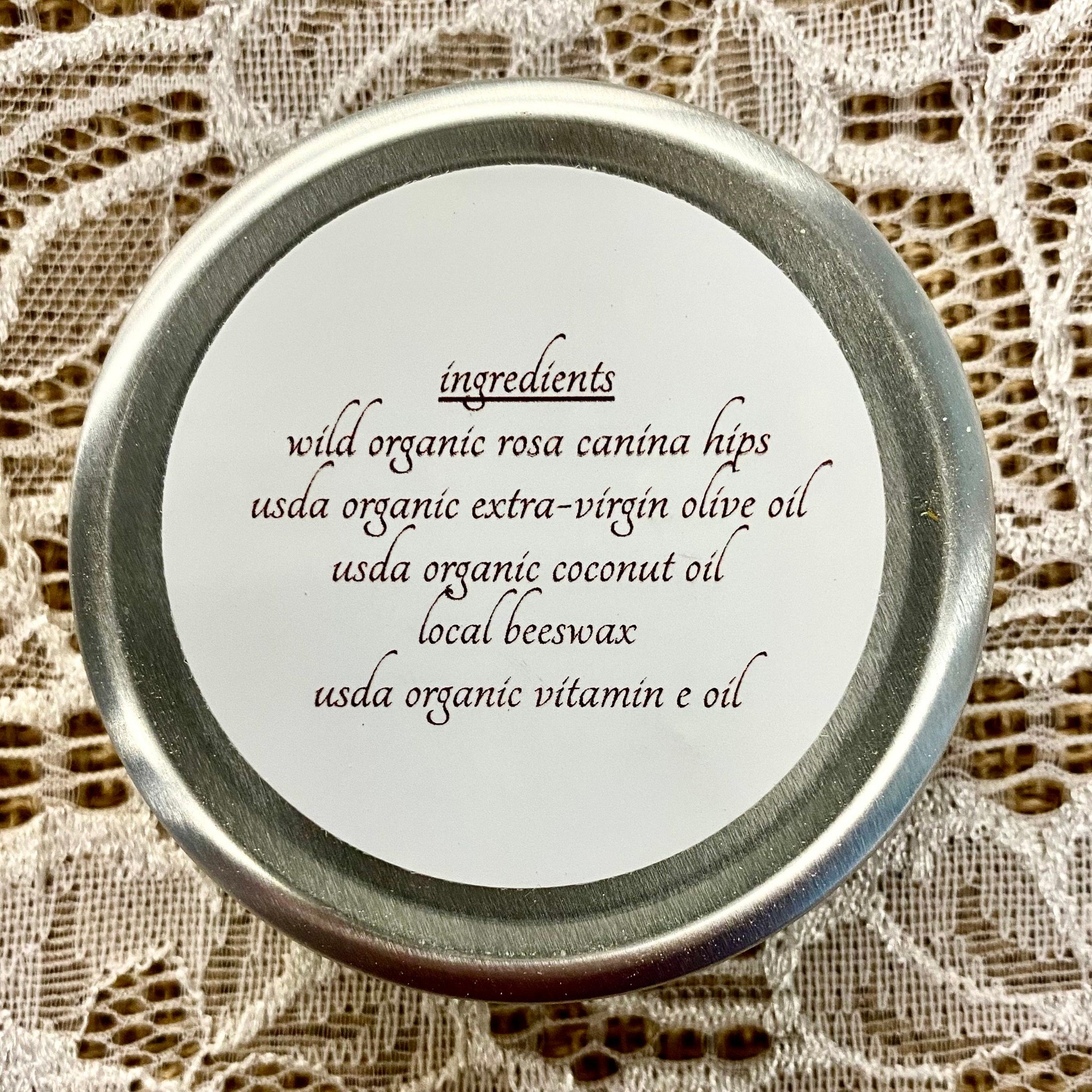 Ingredients label with silver rim, white background, and dark brown text on lace fabric