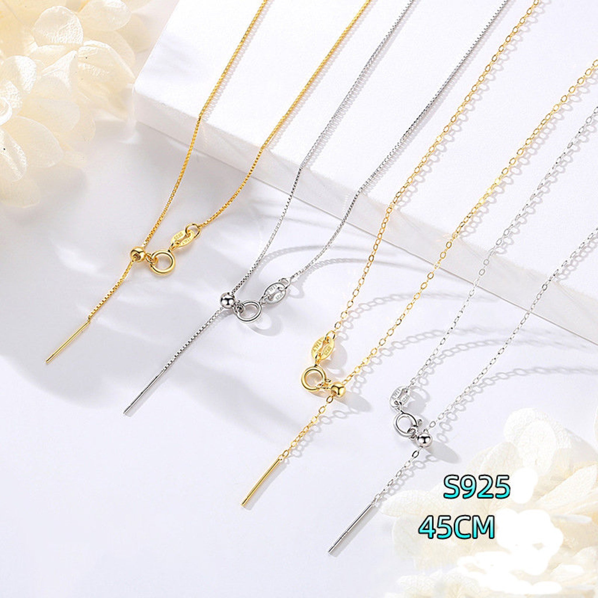 Close-up of sterling silver chain necklace with alternating silver and gold links on a flat surface