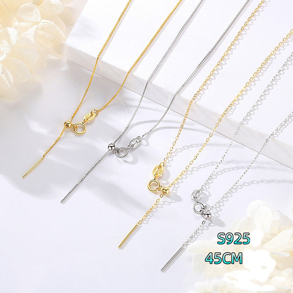 Close-up of sterling silver chain necklace with alternating silver and gold links on a flat surface