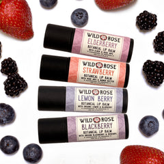 Lip balm gift set with black tubes, berry labels, and fruit on white background