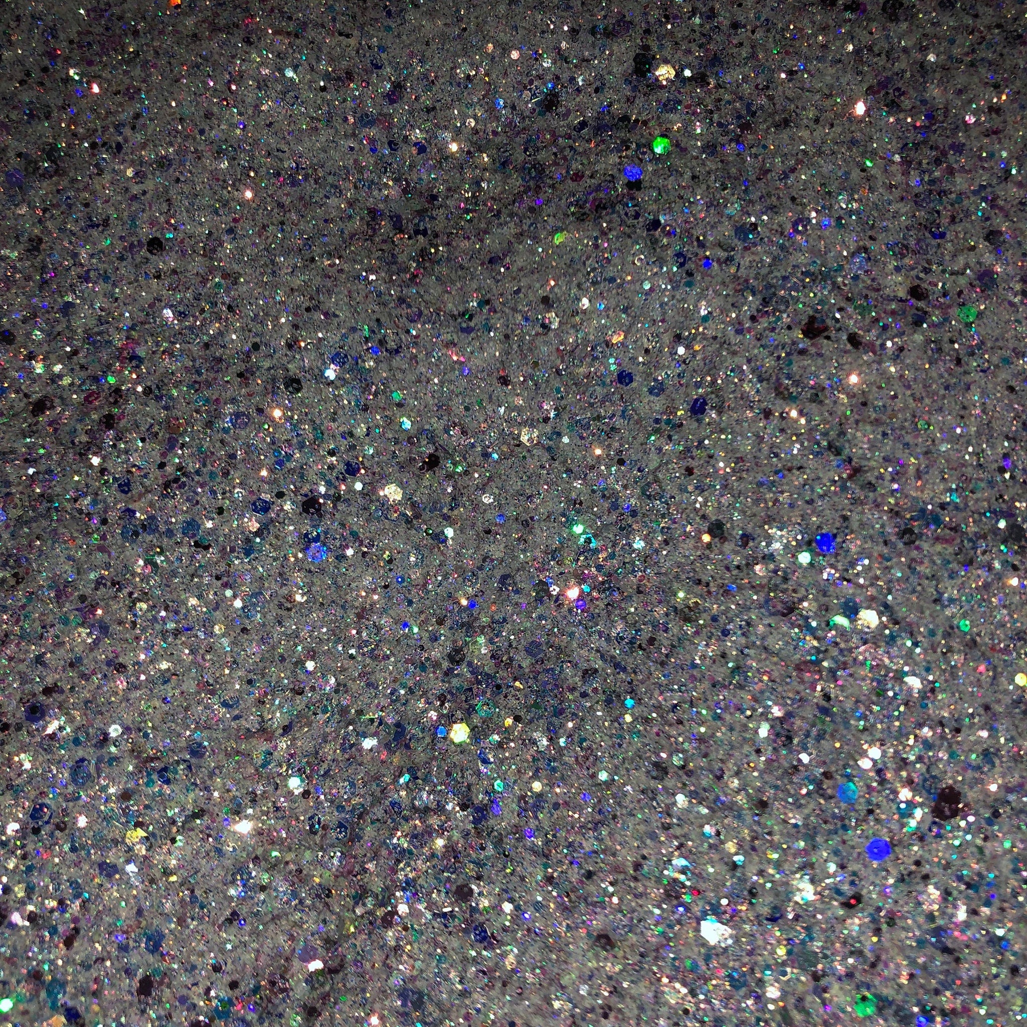Close-up of iridescent white glitter eyeshadow with shimmering blue and pink hues in a compact case