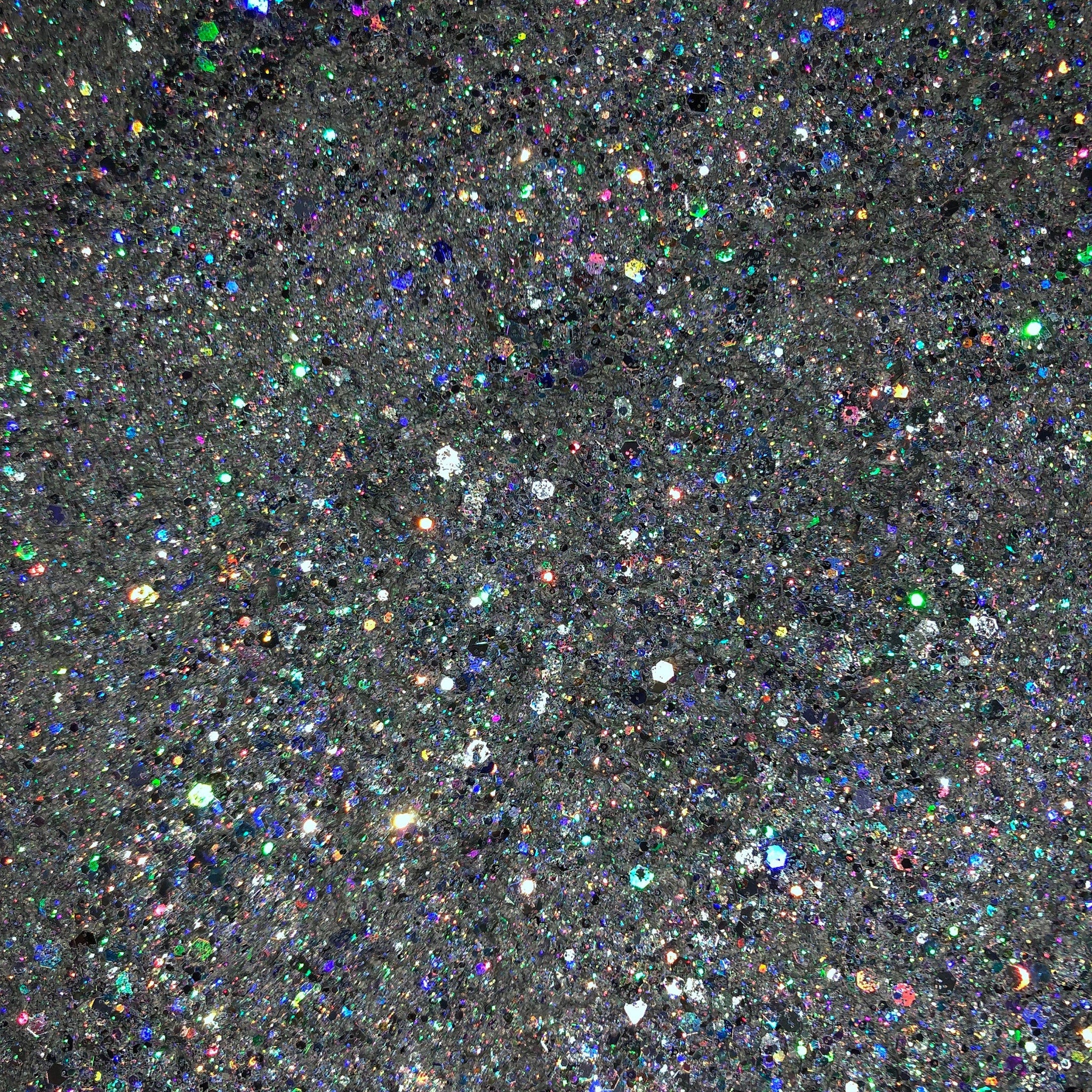 Close-up of holographic silver glitter eyeshadow with intense metallic sheen and reflective particles